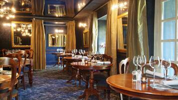 A dining area with round tables, chairs, and chandeliers.
