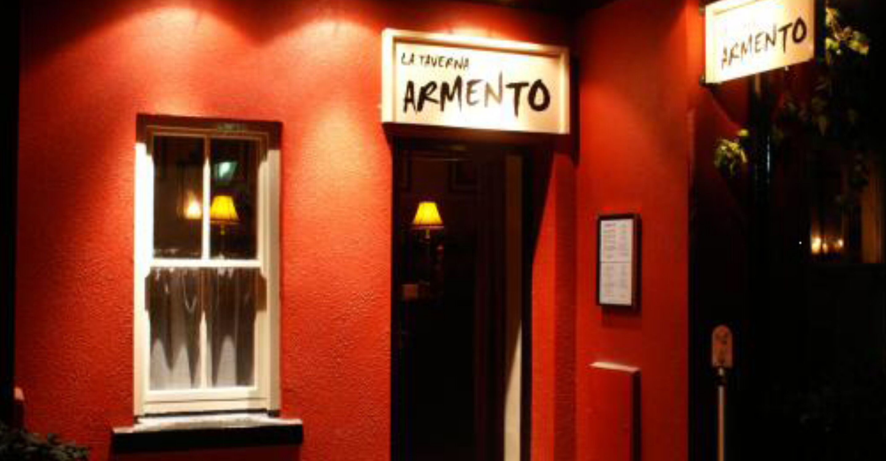 En bygning med rødt ydre og to døre med påskriften "La Taverna Armiento".