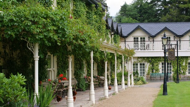A building with a covered outdoor seating area, columns, and a gravel path leading to the entrance. - Brooklodge & Macreddin Village (Macreddin Village)