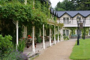 A building with a covered outdoor seating area, columns, and a gravel path leading to the entrance. - Brooklodge & Macreddin Village (Macreddin Village)