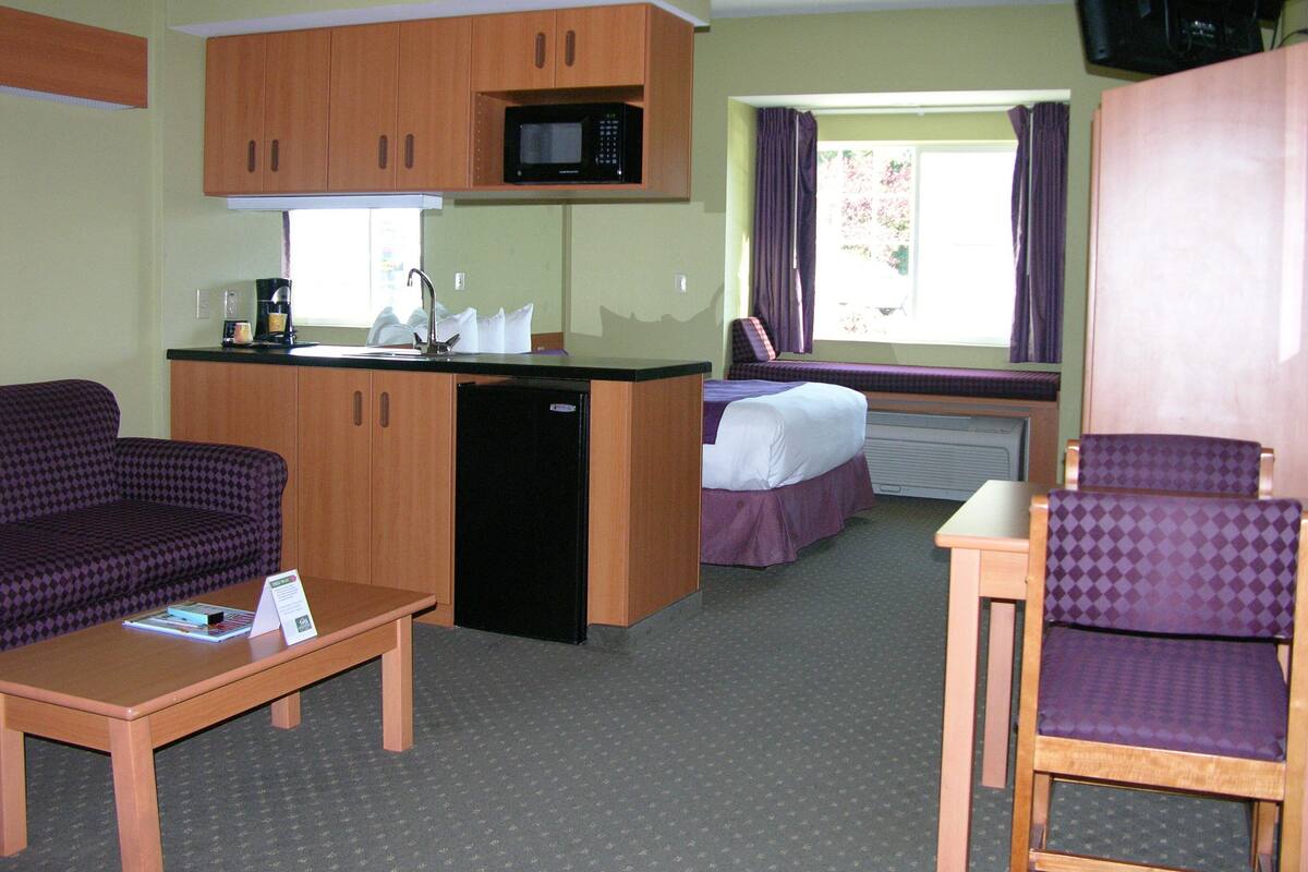 Ett kompakt hotellrum med ett litet pentry, en soffa, en säng och ett litet bord.