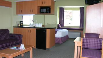Une chambre d’hôtel compacte comprenant un coin cuisine, un canapé, un lit et une petite table.