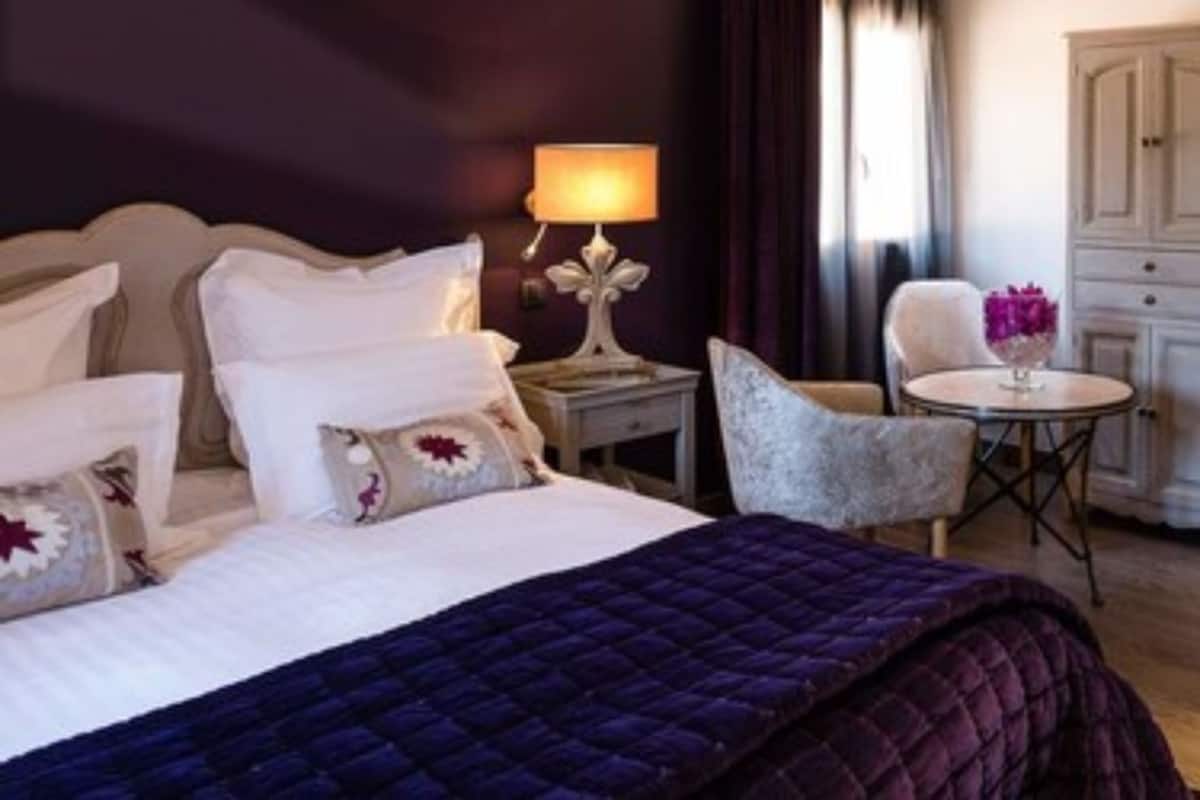 Una habitación de hotel con una cama, un escritorio, una silla y una mesita de noche con una lámpara.