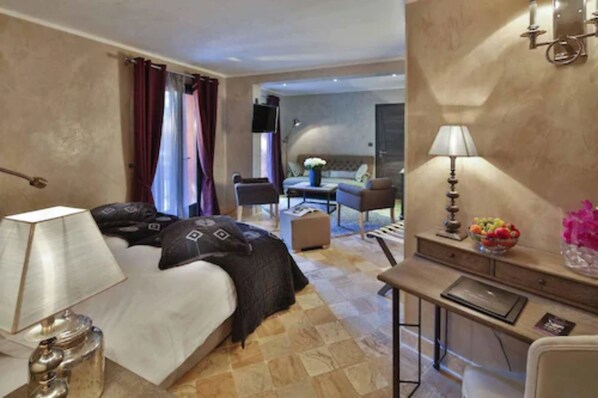 A hotel room with a bed, bedside table, lamp, and a desk with a chair.