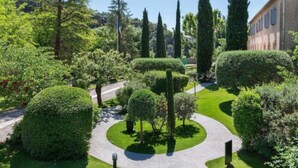 A well-maintained garden with neatly trimmed hedges and trees, a clear pathway, and a building in the background. - Hostellerie Les Gorges de Pennafort (Callas)