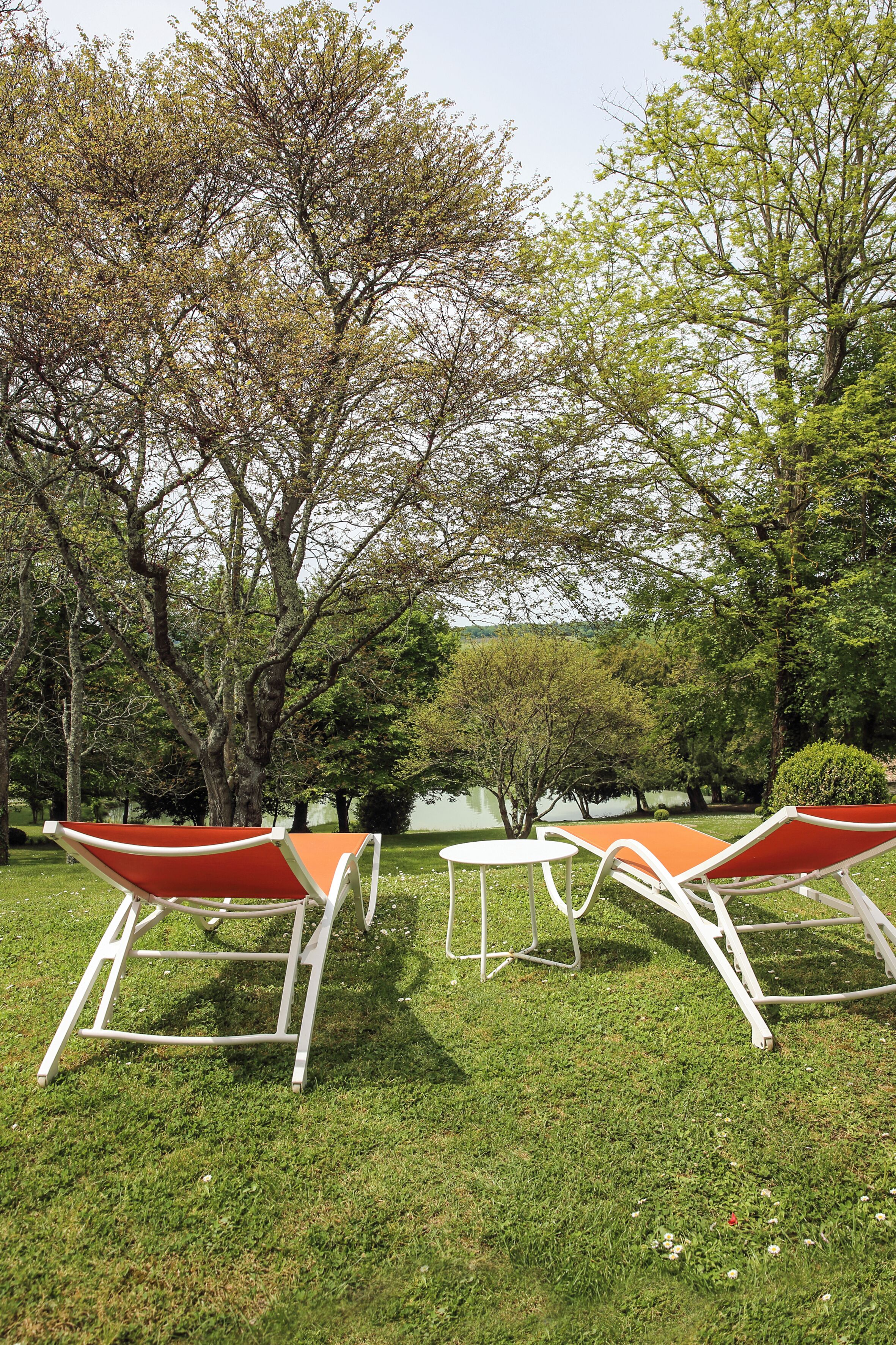 A grassy outdoor area with two white metal chairs and a small white table.