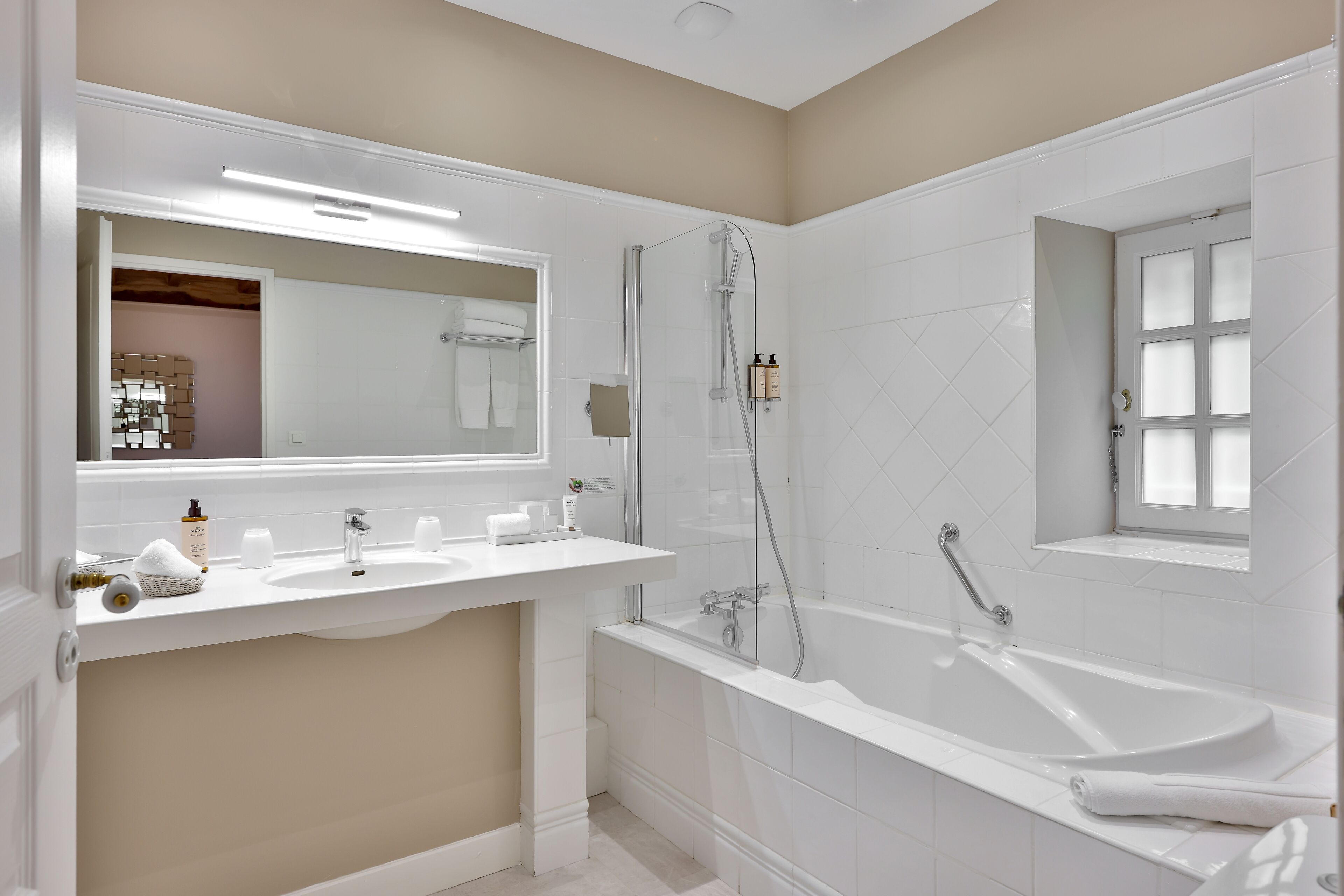Un baño moderno con una bañera grande, una ducha con mampara de vidrio y un tocador con espejo.