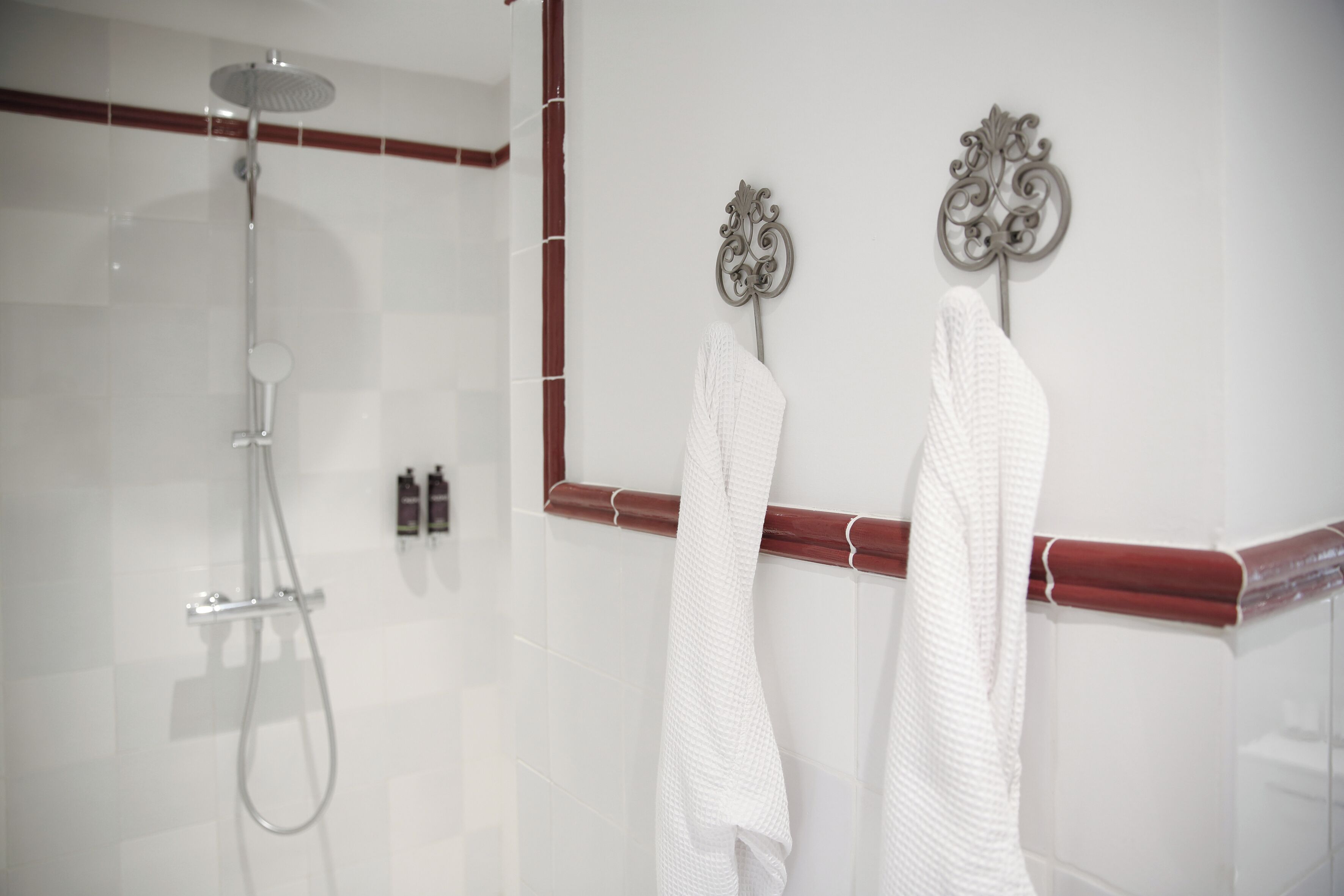 A modern bathroom with a glass shower enclosure, a wooden towel rail, and two white towels hanging on the rail.