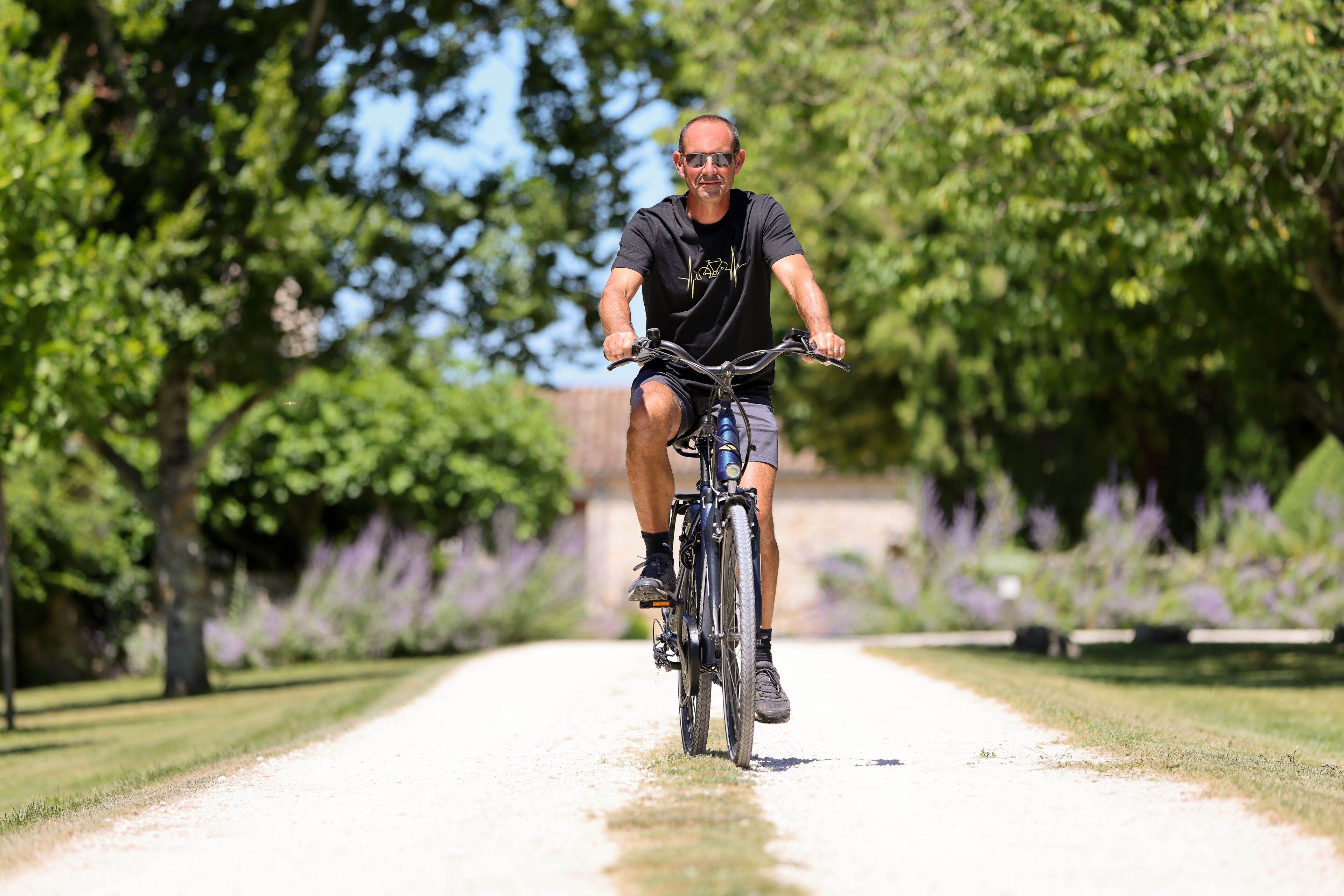 A person riding a bicycle on a paved path surrounded by greenery.