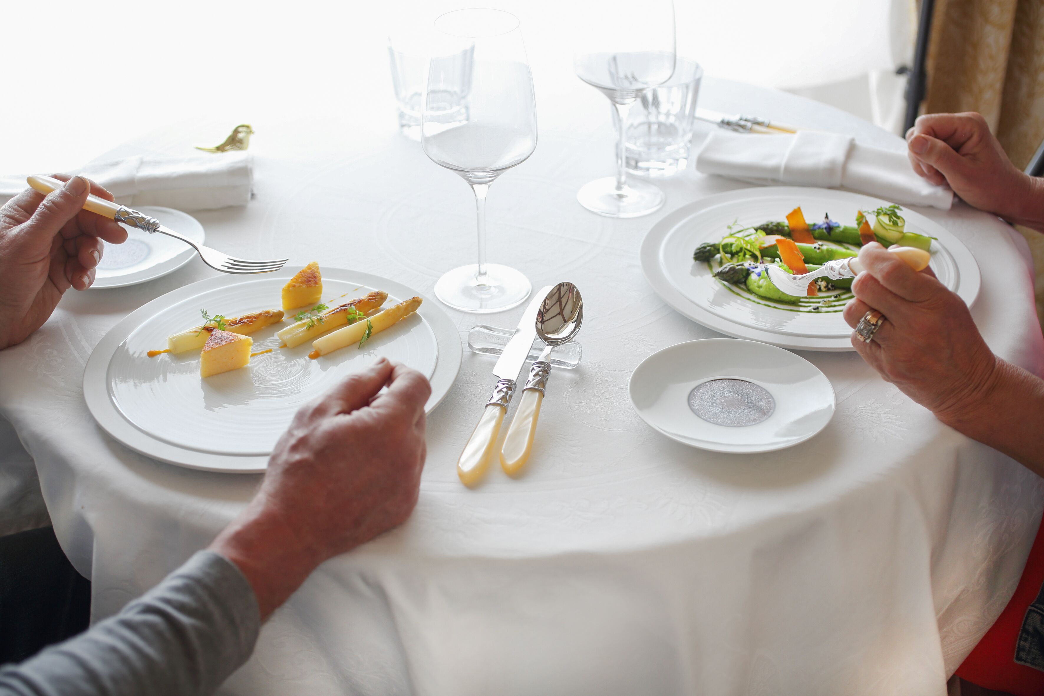 A round dining table with white tablecloth, plates of food, and cutlery.