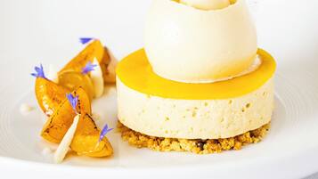 A dessert with a yellow base, a white layer, and a top layer with a flower decoration.