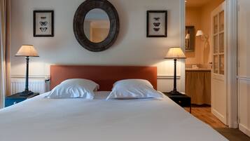 Ein Hotelzimmer mit einem großen Bett, zwei Nachttischen, einem runden Spiegel und zwei gerahmten Schmetterlingsbildern an der Wand.