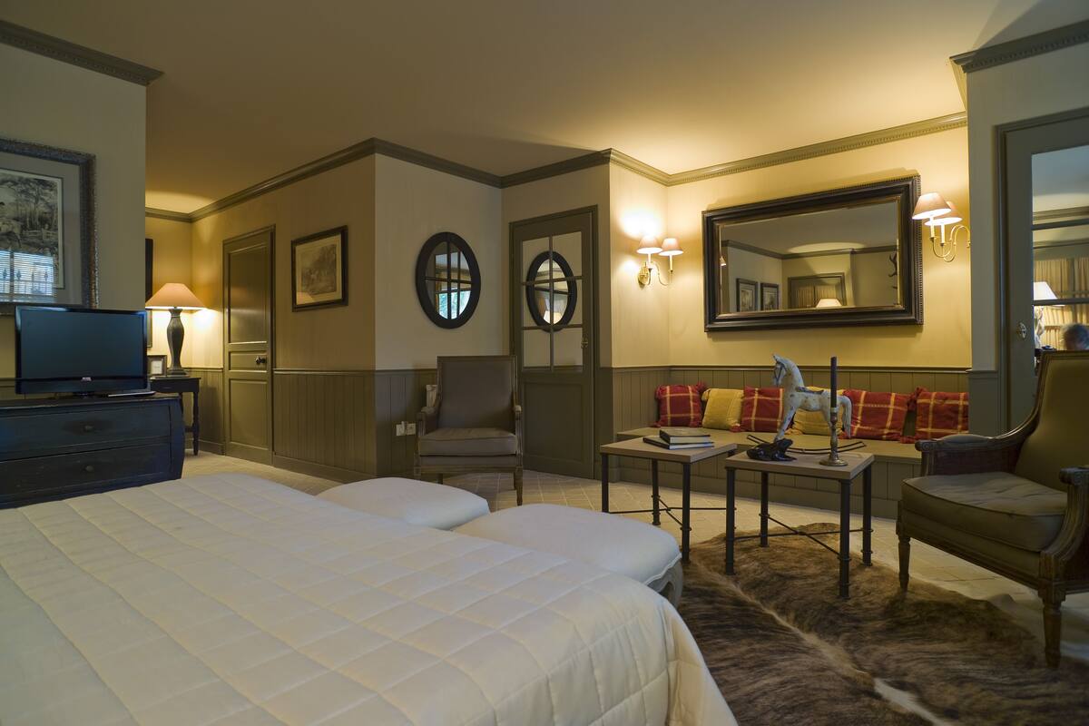 Ein Hotelzimmer mit zwei Betten, einem Schreibtisch, einem Stuhl, einem Fernseher und einem großen Spiegel.