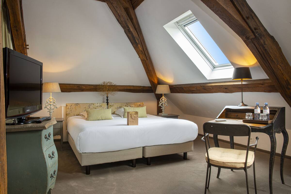 Ein Schlafzimmer mit einem Bett, einem Schreibtisch, einem Stuhl, einem Fernseher und einem Oberlicht.