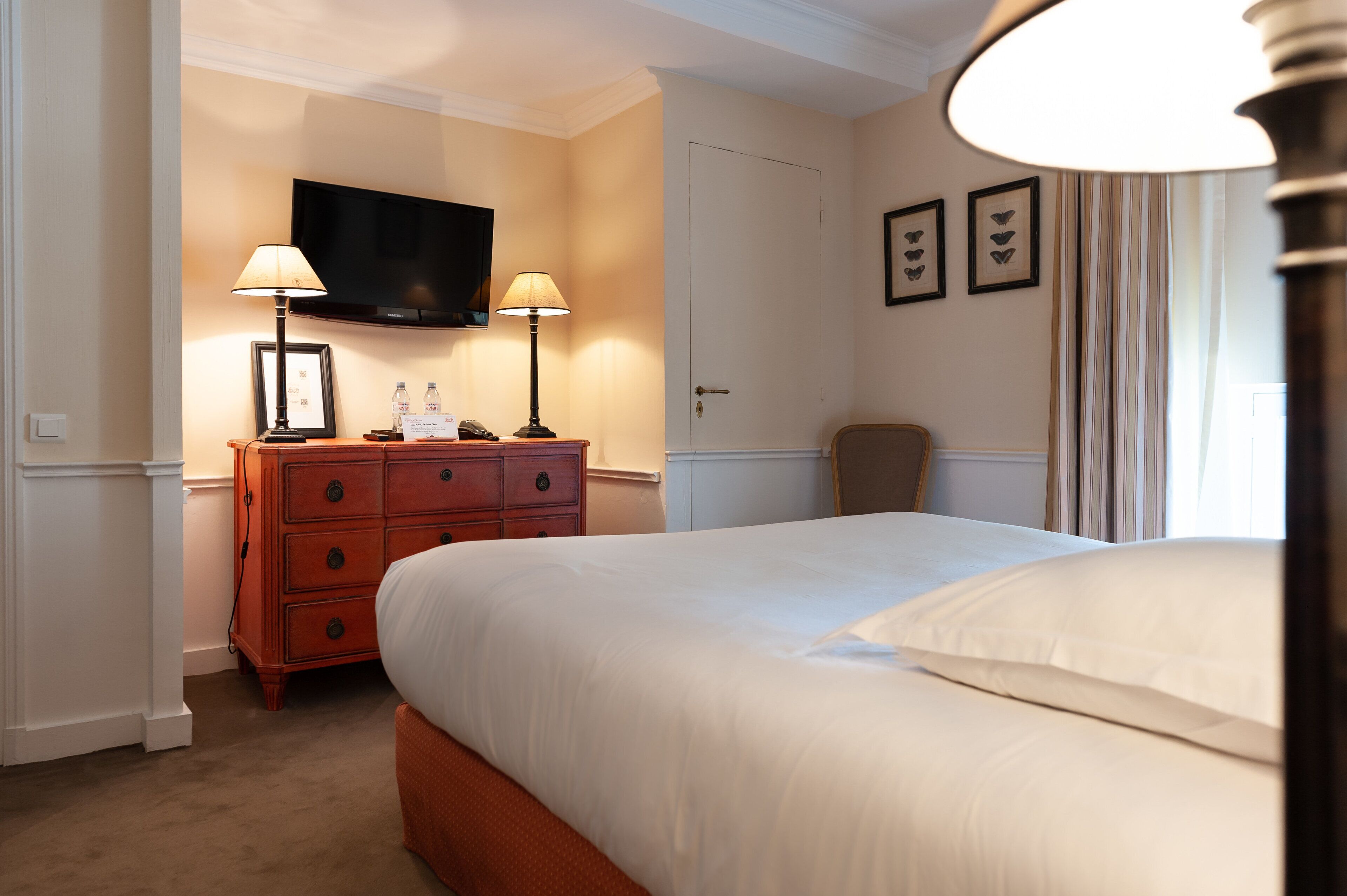 A hotel room with a bed, a dresser, a television, and a door.
