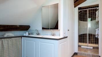 A bathroom with a sink, mirror, and shower enclosure.