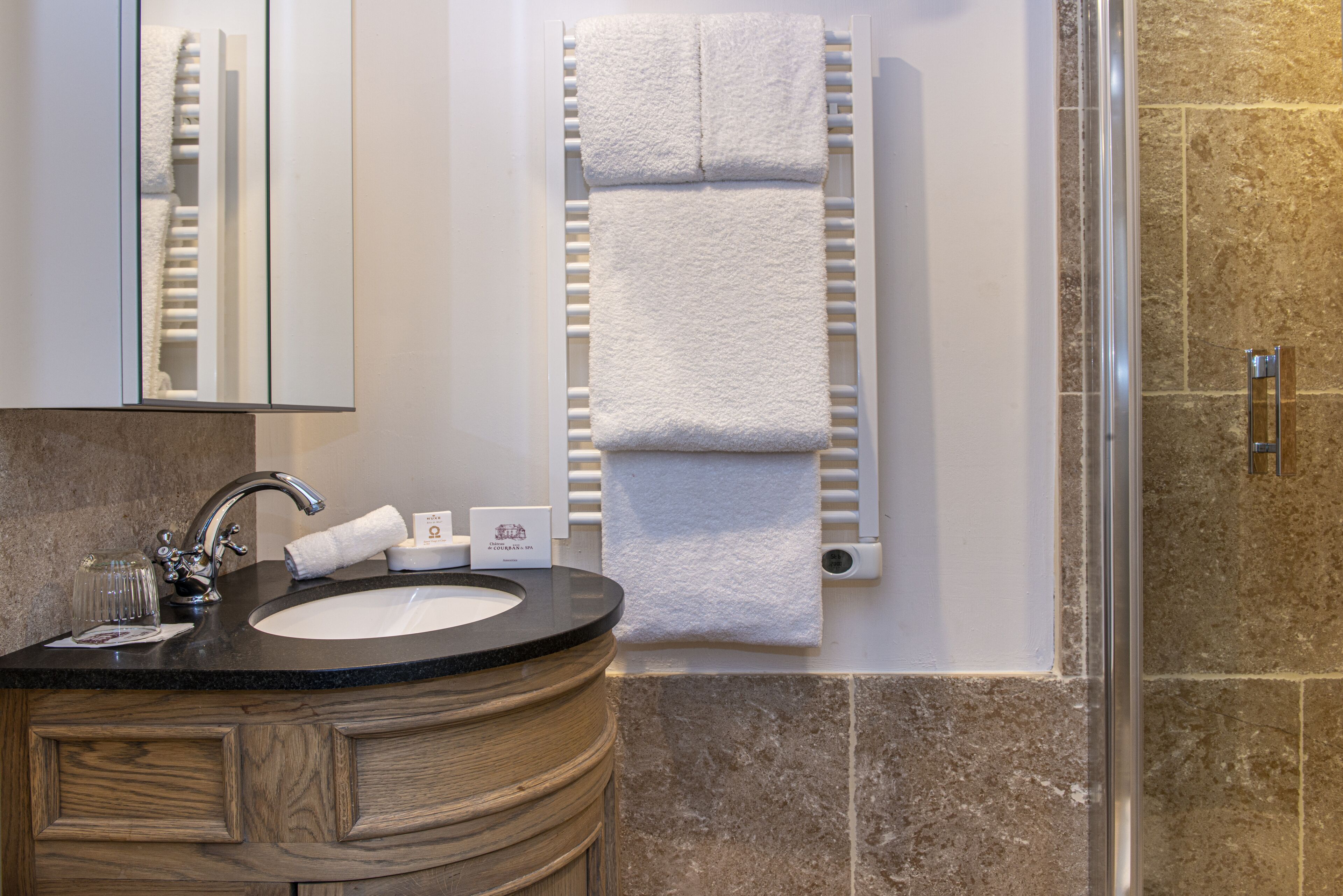 A bathroom with a sink, mirror, towel rack, and shower.