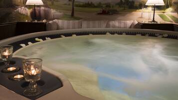 A hot tub with candles, a mural, and two lamps.