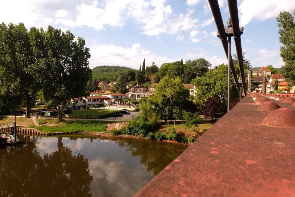 Vista ribeirinha com uma ponte, casas e árvores.