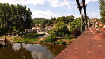 Vista ribeirinha com uma ponte, casas e árvores.