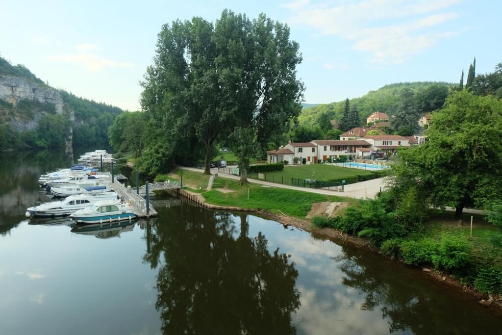 Un hôtel situé au bord de la rivière, avec des bateaux amarrés, une piscine et une végétation luxuriante.