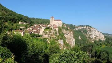 A historic town with a prominent church on a hill, surrounded by lush greenery and a river.