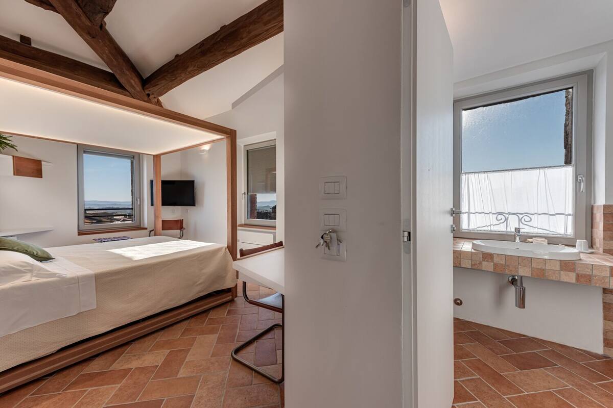 A bedroom with a bed, a desk, and a window with a view.