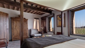 Un dormitorio con una cama grande, muebles de madera, un ventanal con vistas y un techo rústico.