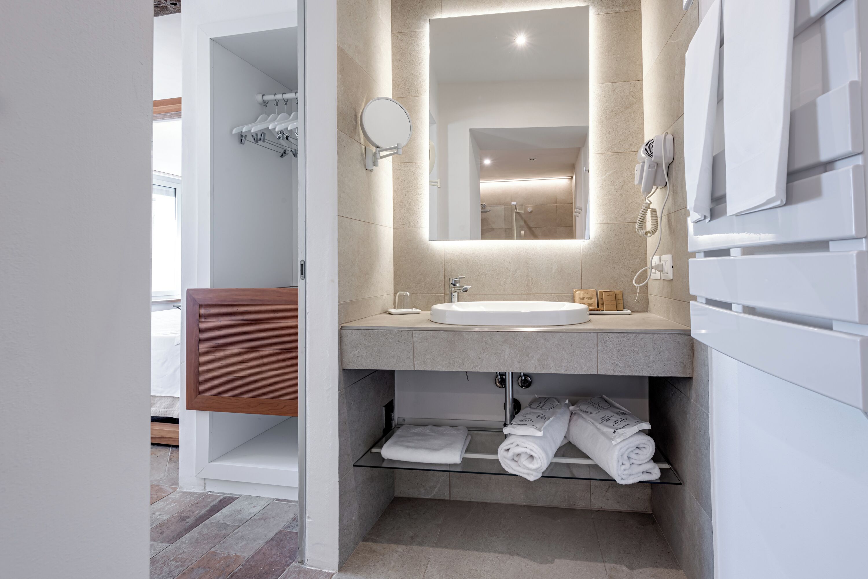 Een moderne badkamer met een grote spiegel, een wastafel, een handdoekrek en een douche.