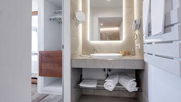 Een moderne badkamer met een grote spiegel, een wastafel, een handdoekrek en een douche.