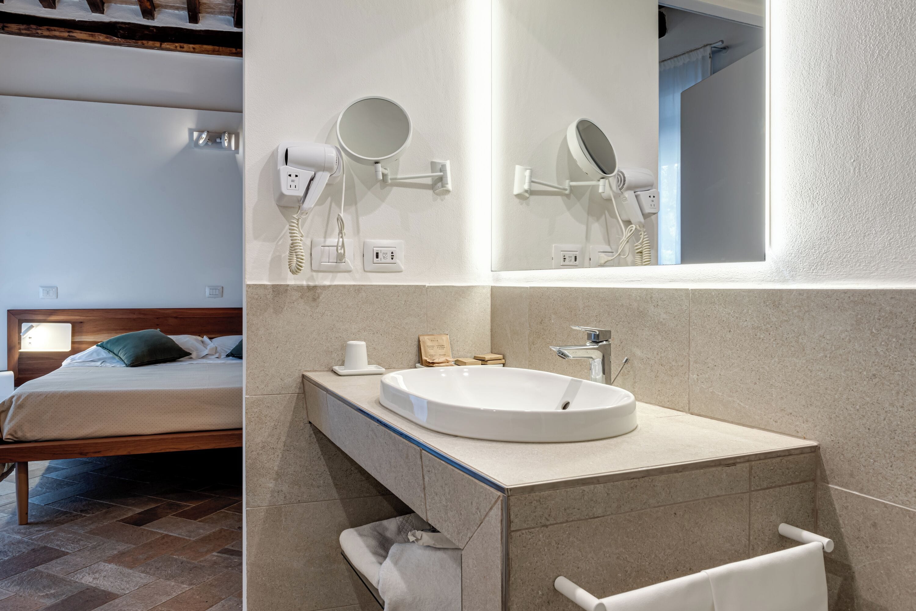 Un baño moderno con un espejo grande, un lavamanos y un secador de pelo montado en la pared.
