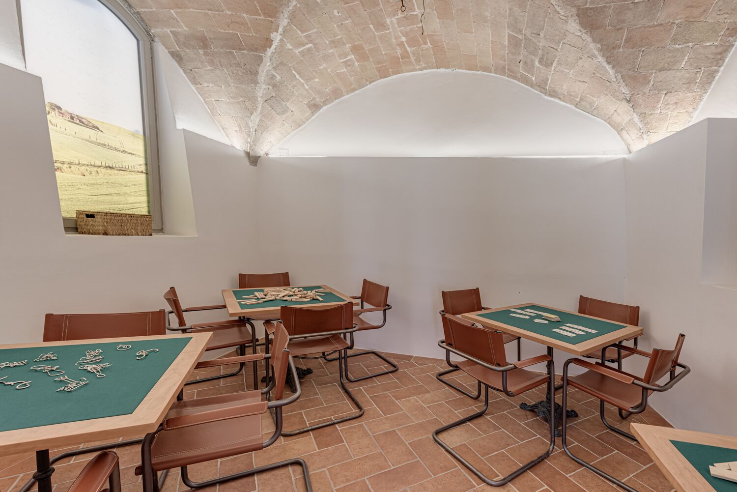 A room with four green felt-covered tables and chairs, arranged in pairs.