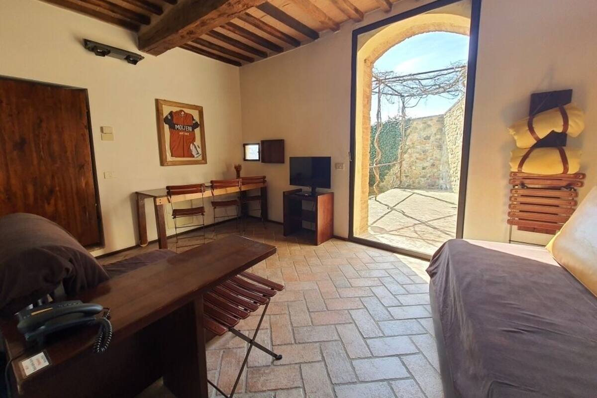 A cozy room with a wooden ceiling, a large window, a wooden table, a bed, and a TV.
