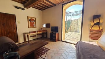 Um quarto aconchegante com teto de madeira, uma janela grande, uma mesa de madeira, uma cama e uma TV.