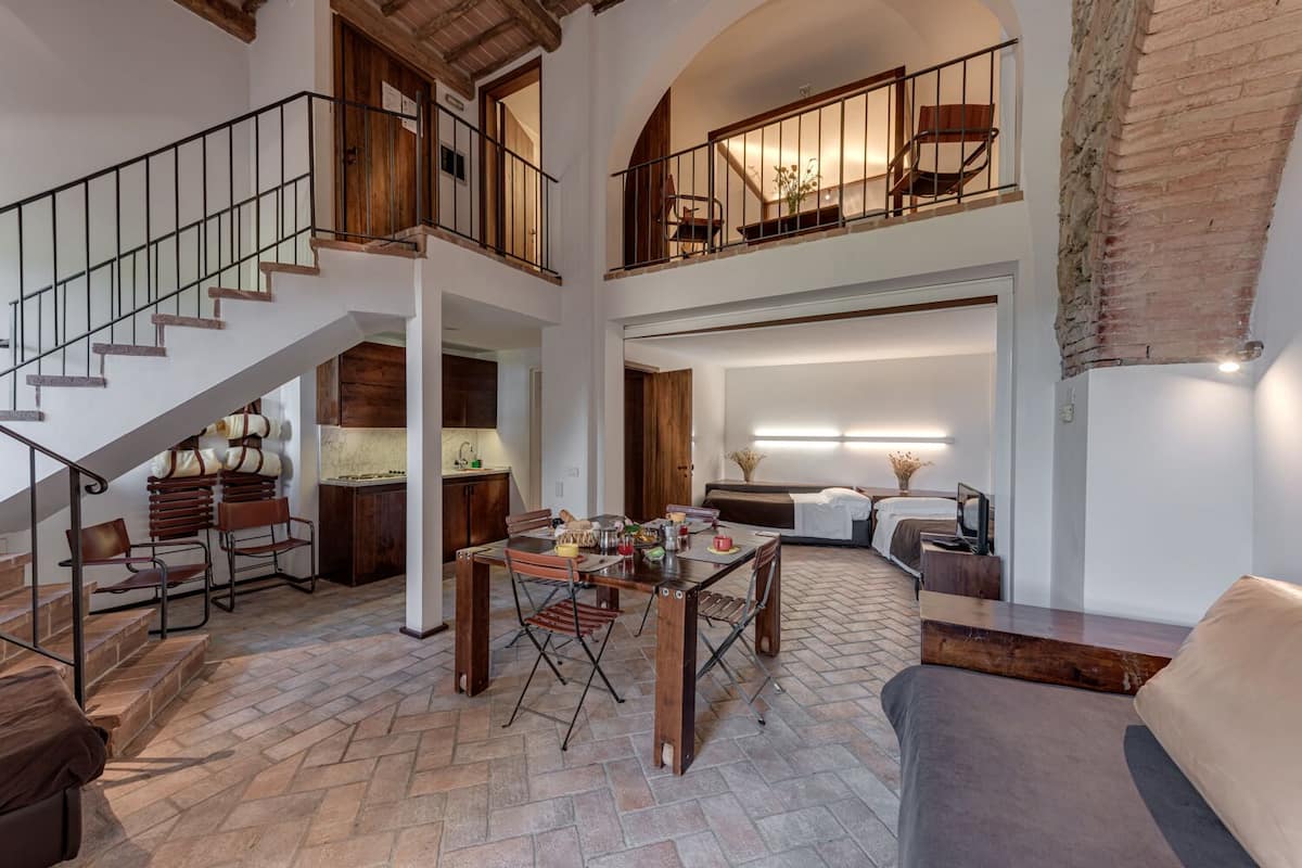 A spacious loft-style living area with a dining table, multiple seating options, and a staircase leading to an upper level.