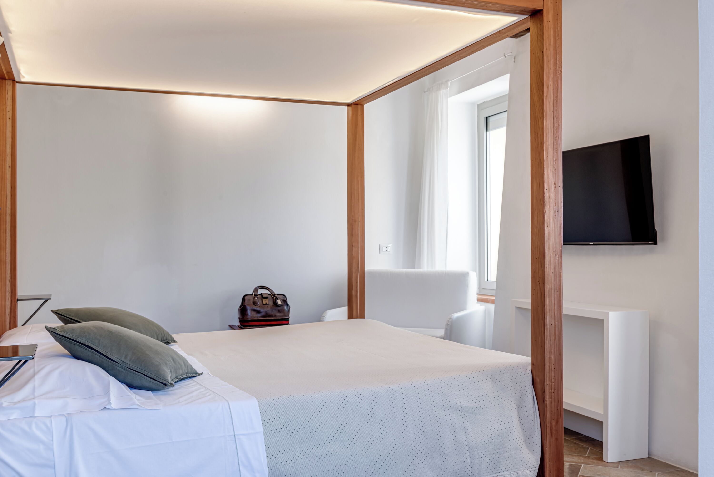 A bedroom with a bed, a chair, a TV, and a small table.