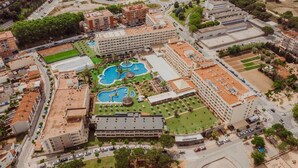 Vista aérea de un hotel con varias construcciones, una piscina central y abundante vegetación.