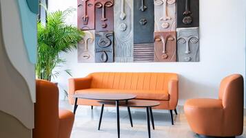 Una sala de estar moderna con un sofá naranja, una mesa de centro redonda y sillones a juego. Una gran obra de arte abstracto decora la pared detrás del sofá.