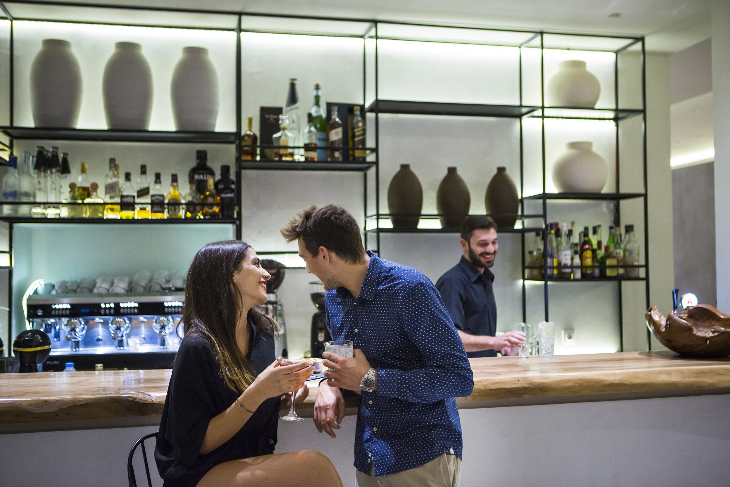 A bar area with shelves of bottles and vases.