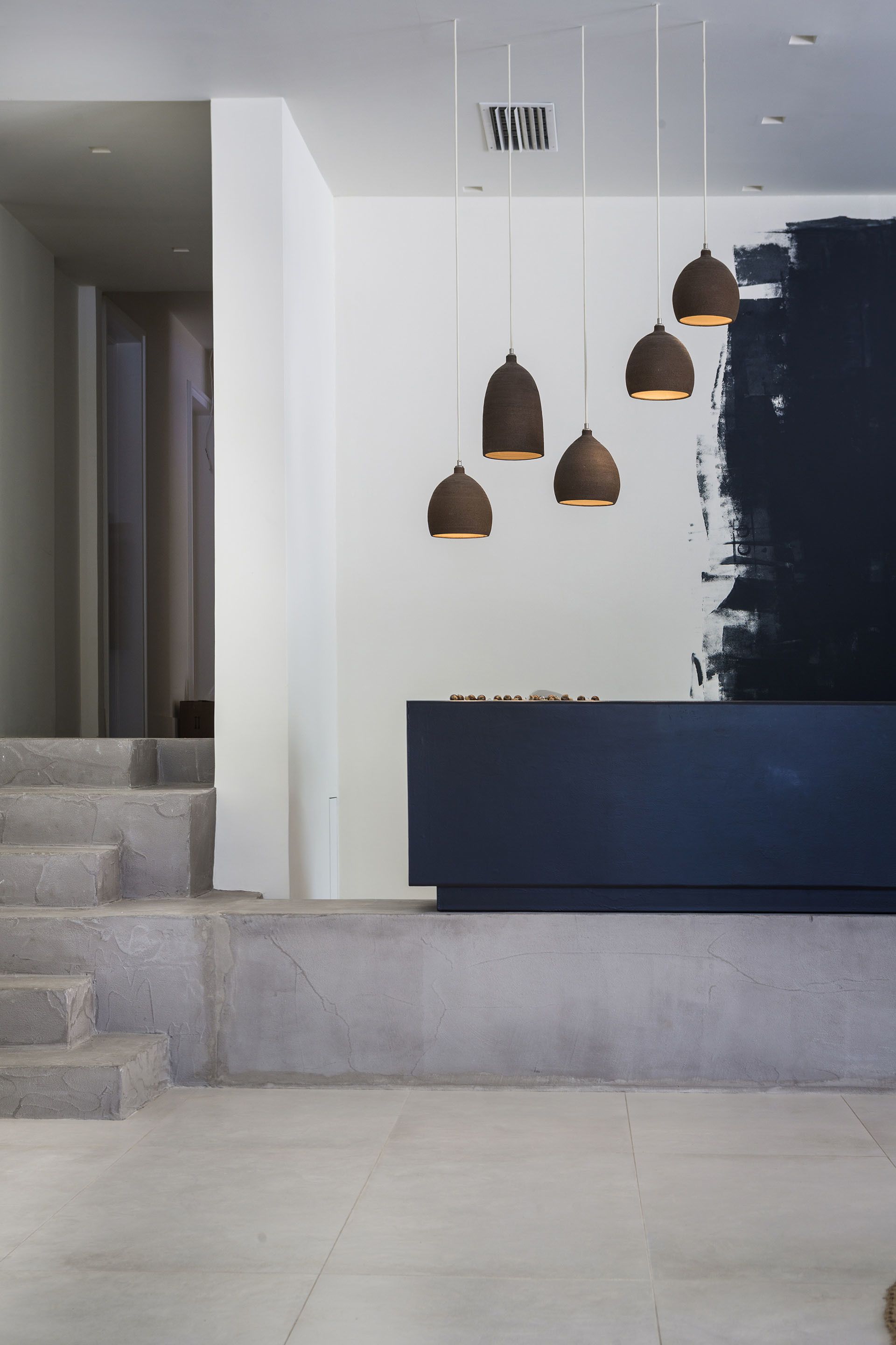 A modern reception area with a dark reception desk, a large abstract painting on the wall, and a staircase leading to another level.