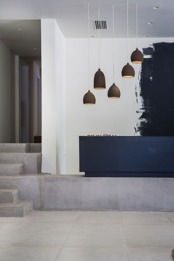 Una moderna área de recepción con un mostrador oscuro, un gran cuadro abstracto en la pared y una escalera que sube a otro nivel.