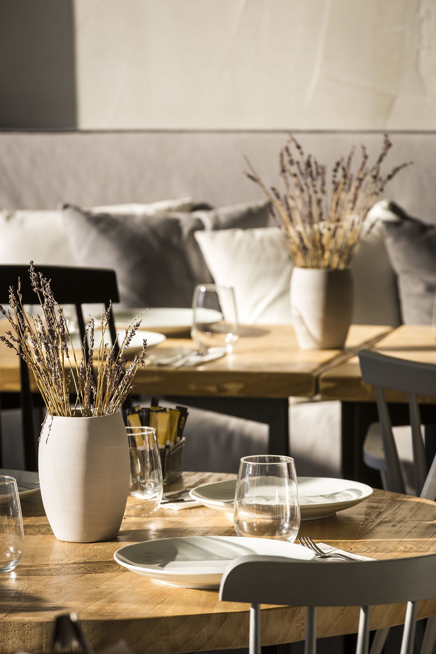 Een eettafel met een vaas gedroogde planten, lege wijn glazen en net gezet servies.