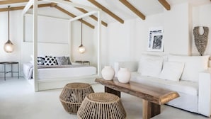Un dormitorio moderno con una cama con dosel blanco, un sofá blanco y una mesita de madera.