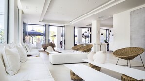 Un salón amplio con un sofá blanco, sillas de mimbre y un ventanal que ofrece vistas al exterior.