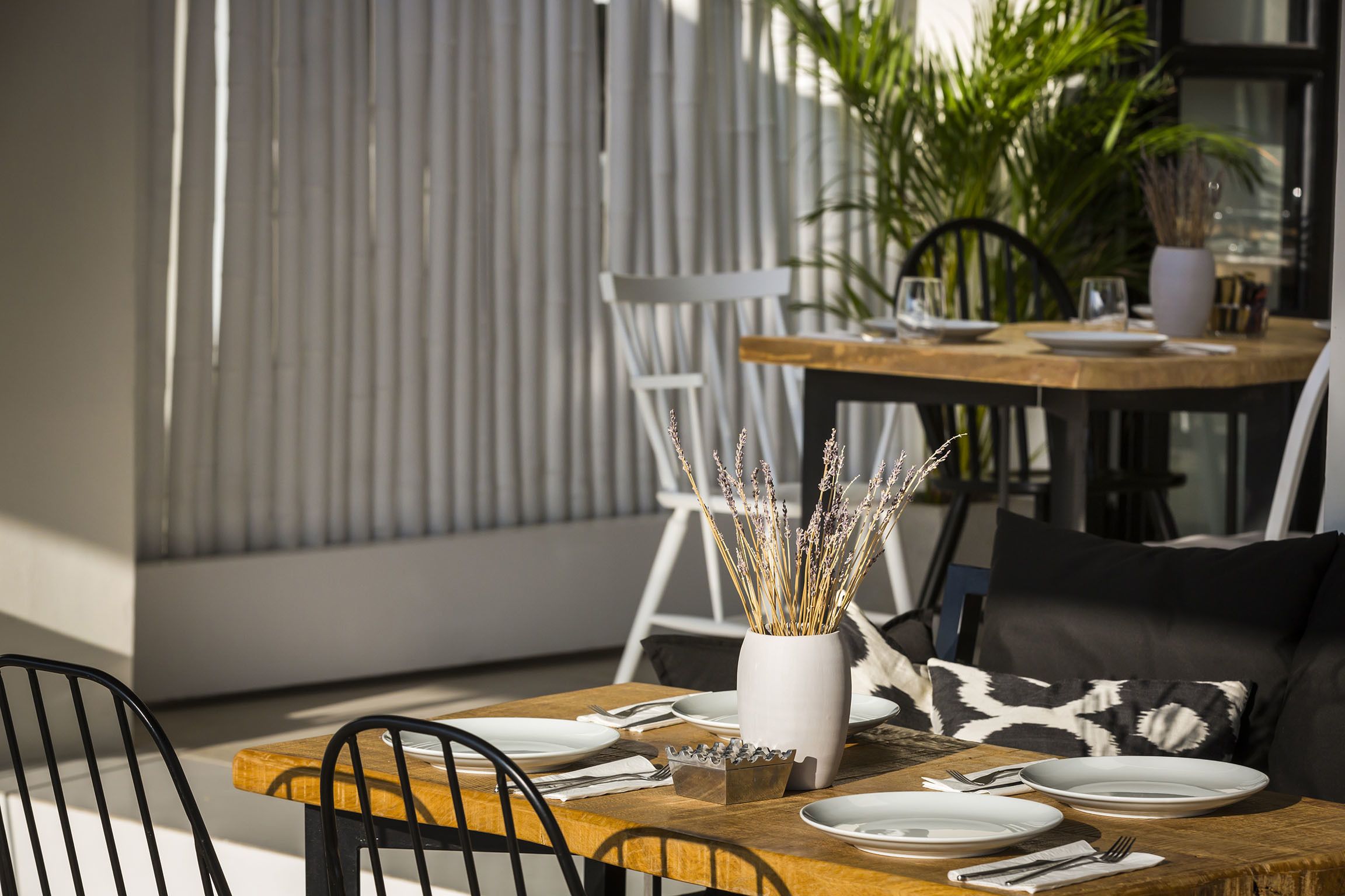 Una mesa de comedor dispuesta con platos, cubiertos y un florero con plantas secas.