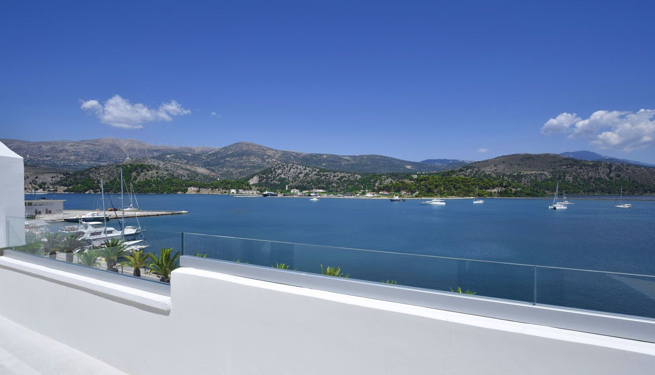 Vista costera con barcos, un puerto deportivo y montañas al fondo.