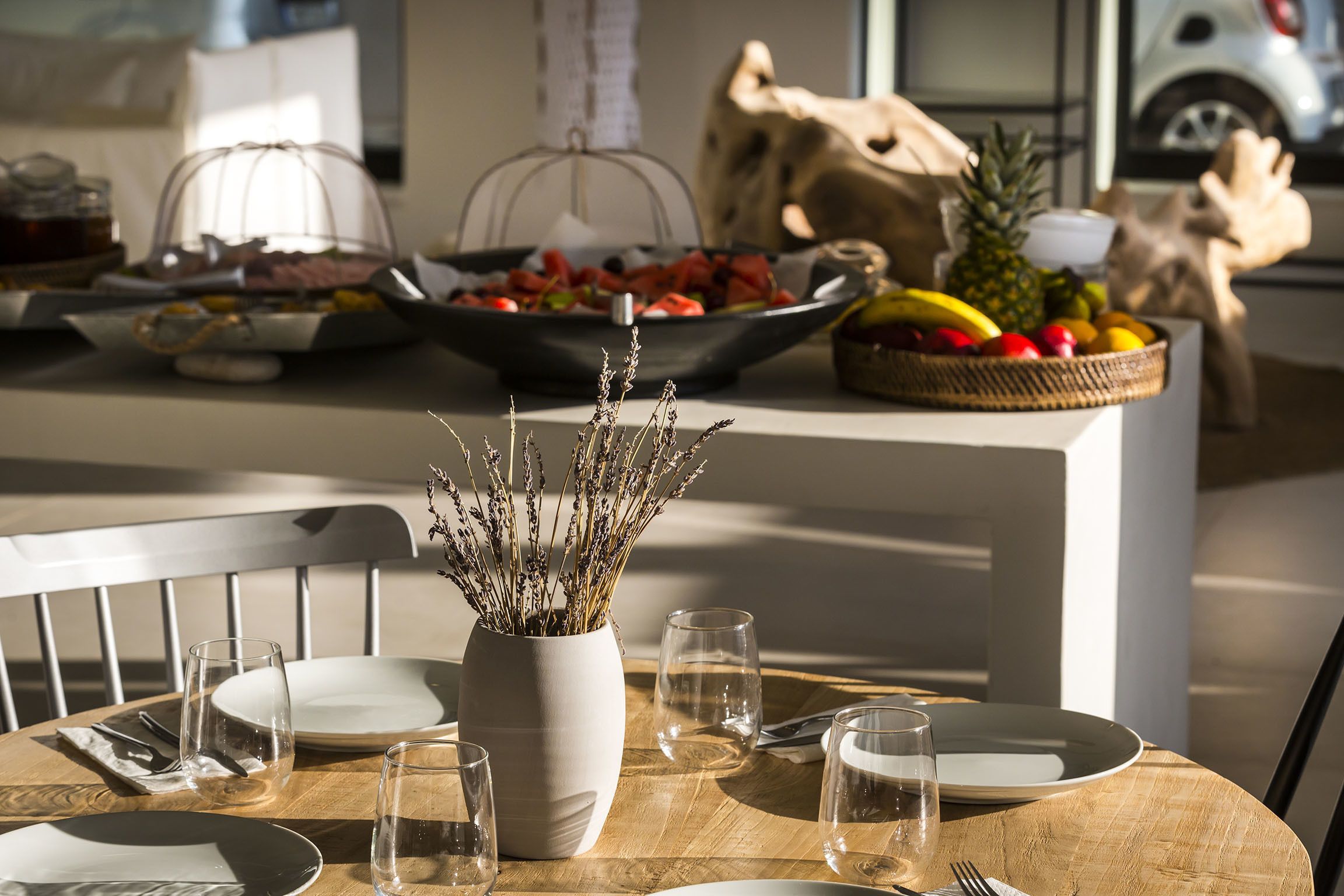 A dining table set with plates, cutlery, and a vase of dried flowers.