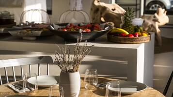 A dining table set with plates, cutlery, and a vase of dried flowers.