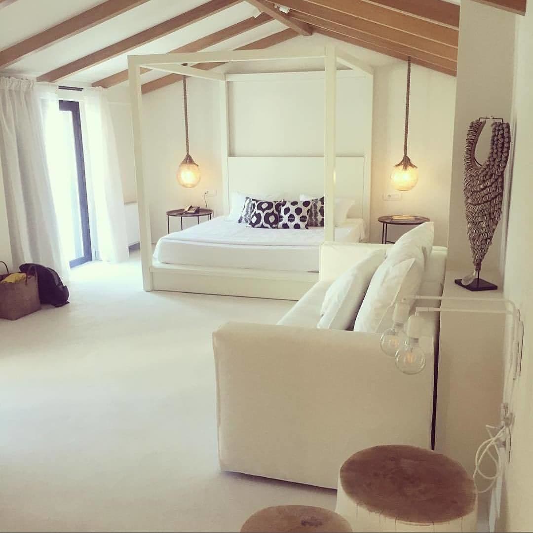 A spacious bedroom with a large bed, a sitting area, and a decorative wall piece.
