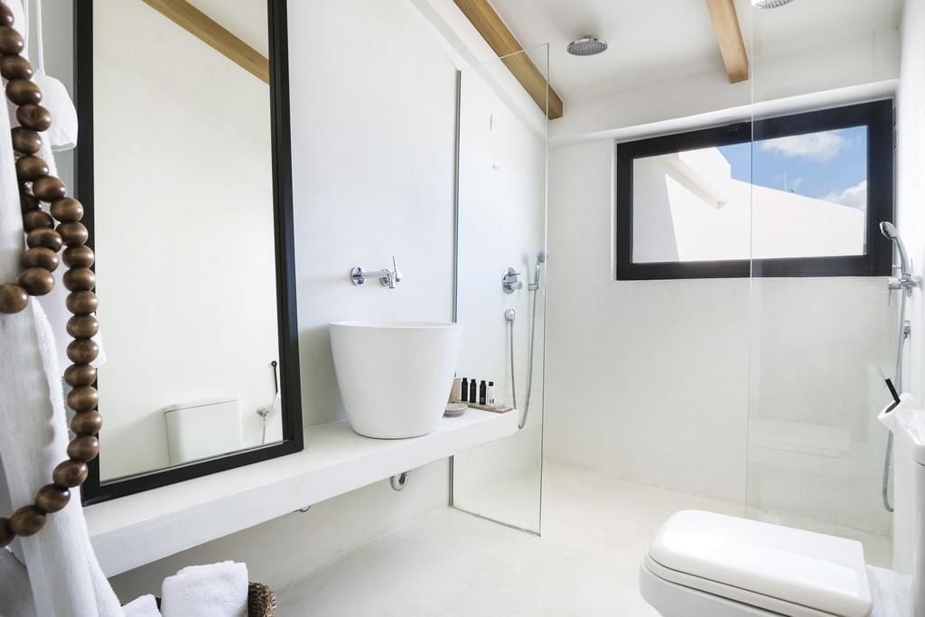 A modern bathroom with a large mirror, a white sink, and a glass shower enclosure.